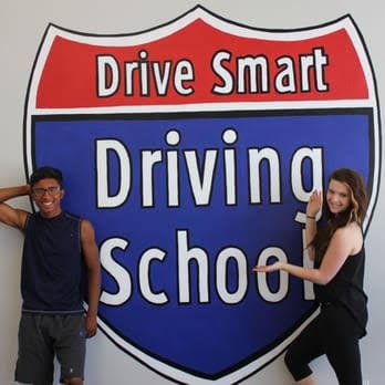 Two students beside the Drive Smart Driving School sign